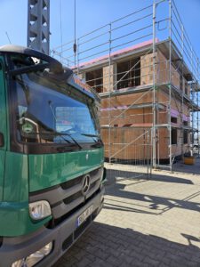 Rohbau einer Zahnarztpraxis aus Porotonsteinen im Vordergrund steht ein grüner LKW des Unternehmens